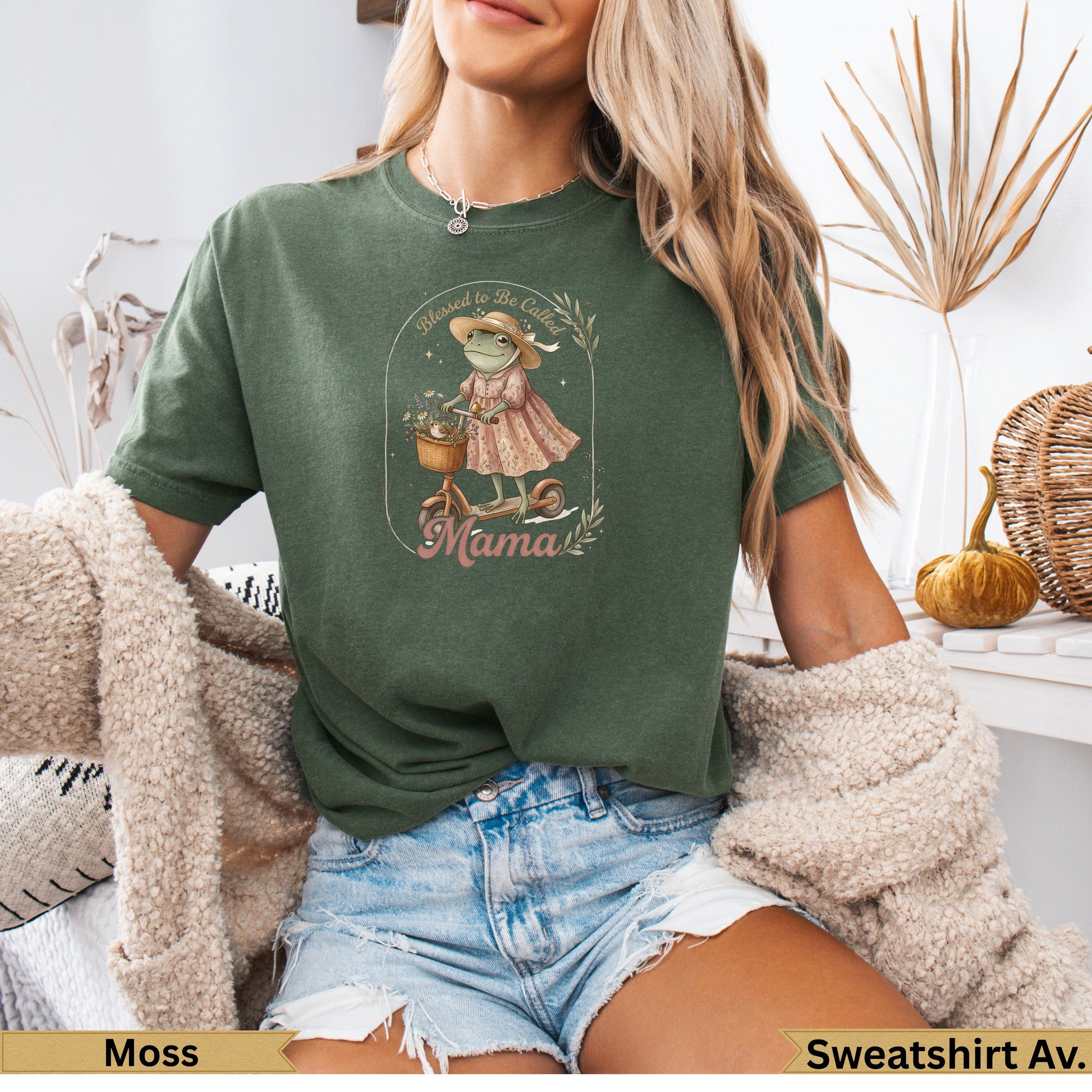 Green sweatshirt featuring a graphic of a frog on a scooter with flowers and the text "Mama".