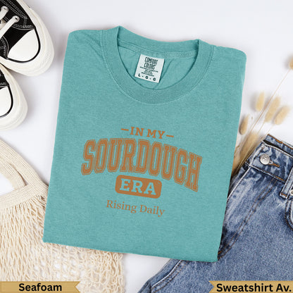 Teal graphic t-shirt with "In My Sourdough Era" and "Rising Daily" text.