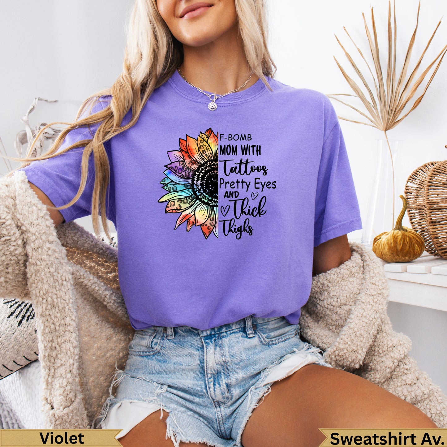 Purple graphic tee with sunflower and "Mom with Tattoos, Pretty Eyes and Thick Thighs" text.