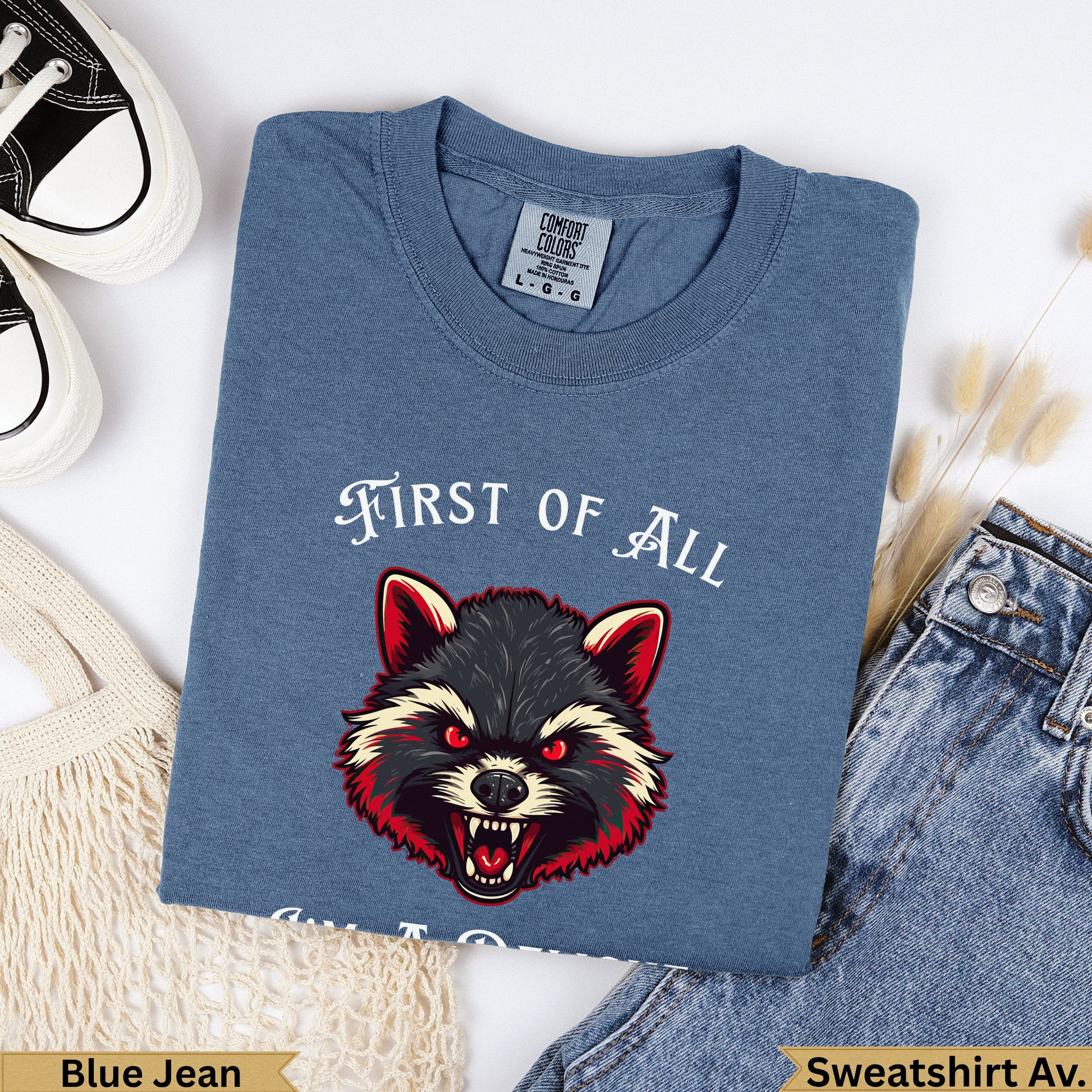 Blue jean t-shirt with a snarling raccoon and "FIRST OF ALL" text.