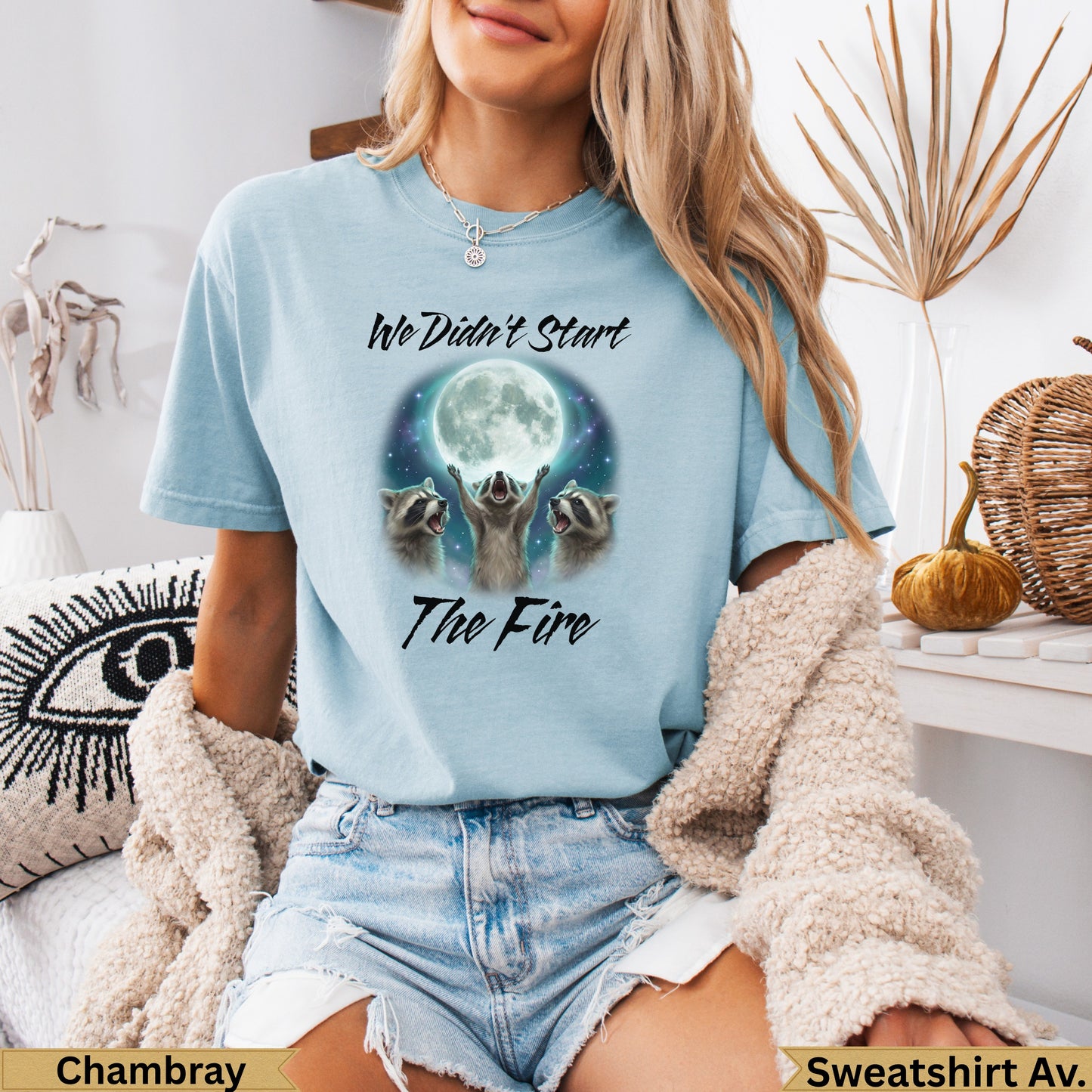 Light blue t-shirt with raccoons reaching for moon and text "We didn't start the fire."