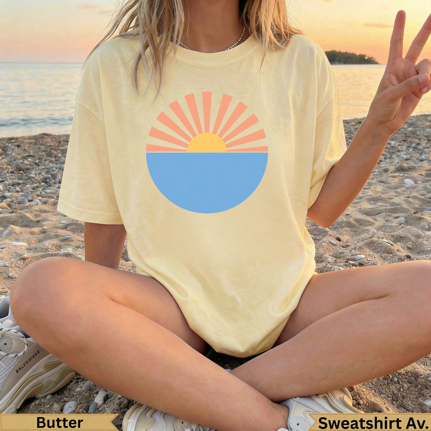 Yellow sweatshirt with a sun and ocean graphic, worn by a person on a beach.