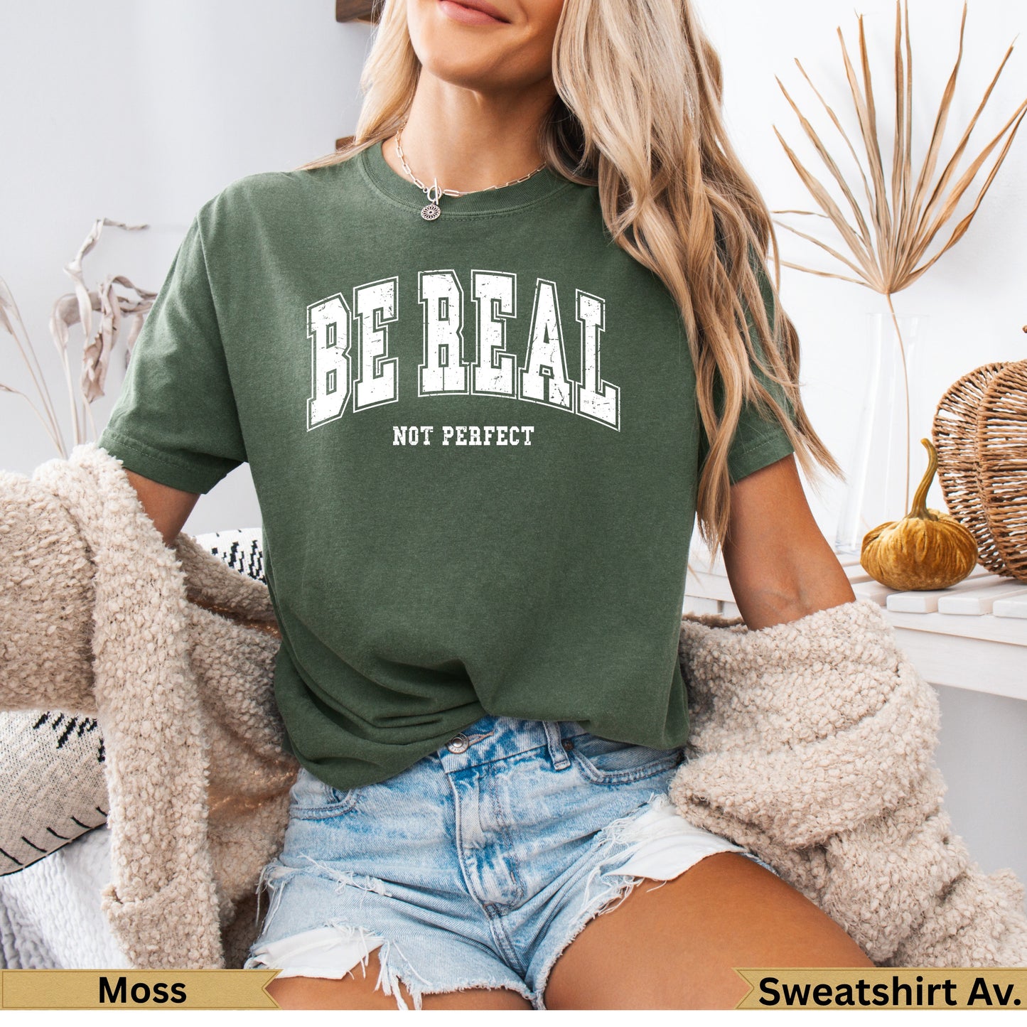 Green t-shirt with "BE REAL NOT PERFECT" text, worn by a woman.