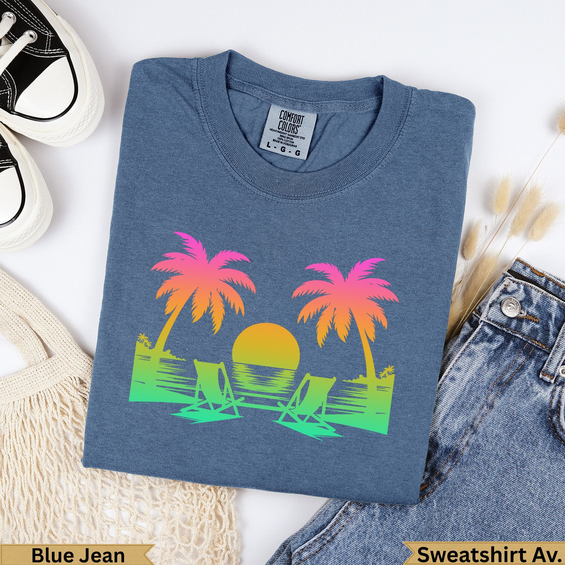 Blue sweatshirt with gradient palm trees, sun, and beach chairs.