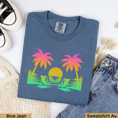 Blue sweatshirt with gradient palm trees, sun, and beach chairs.