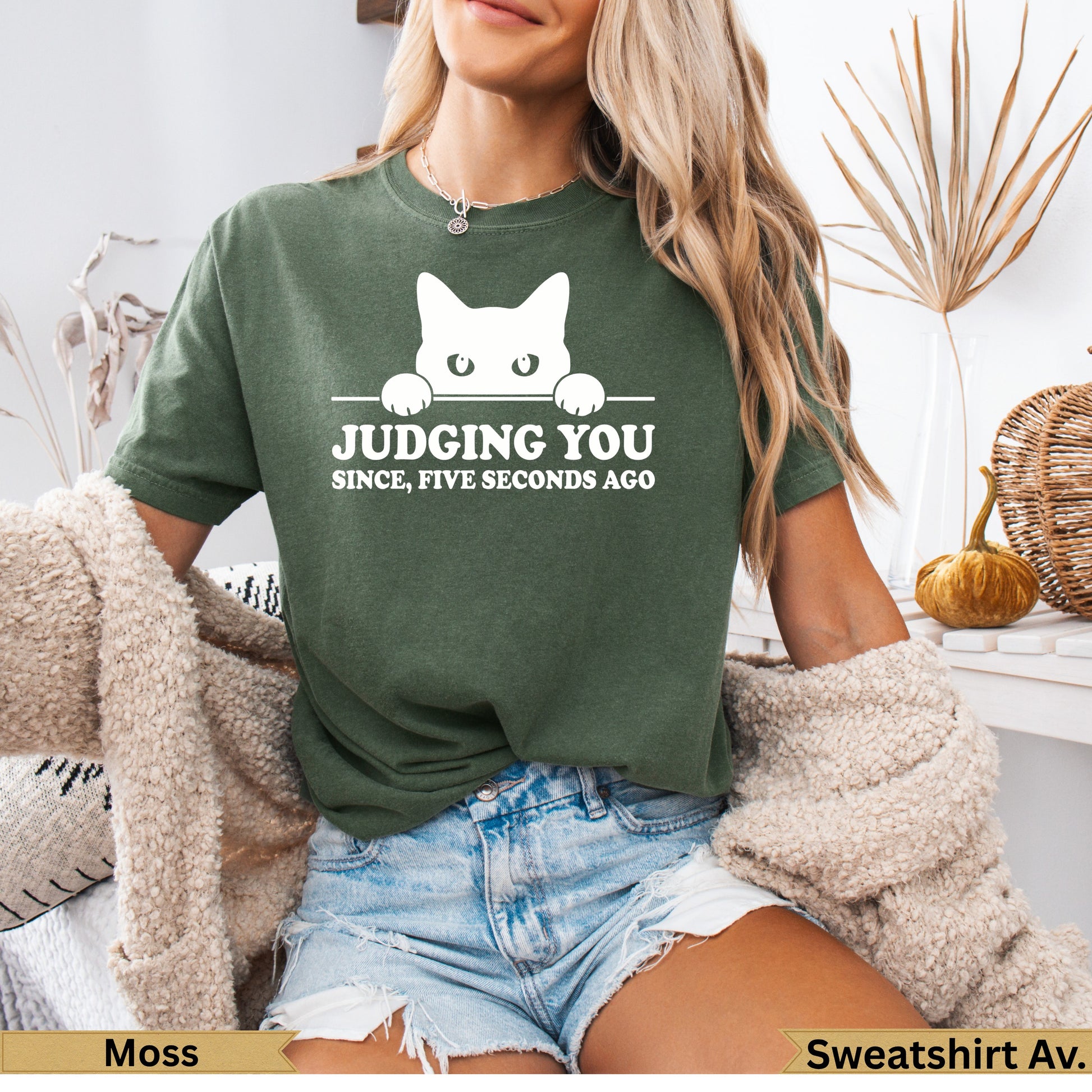 Moss green t-shirt with white cat peeking over text "Judging you since five seconds ago."