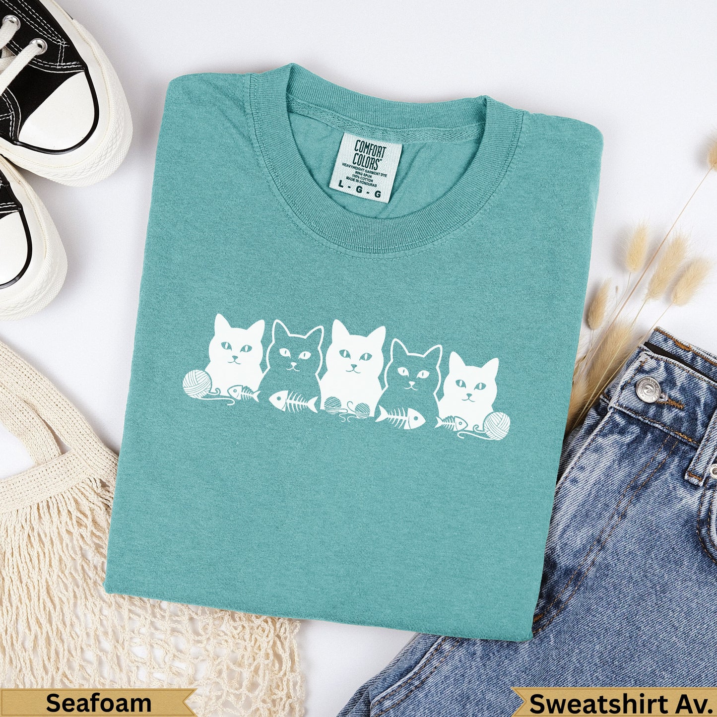 Teal Comfort Colors t-shirt with five white cat illustrations and "Seafoam" text.
