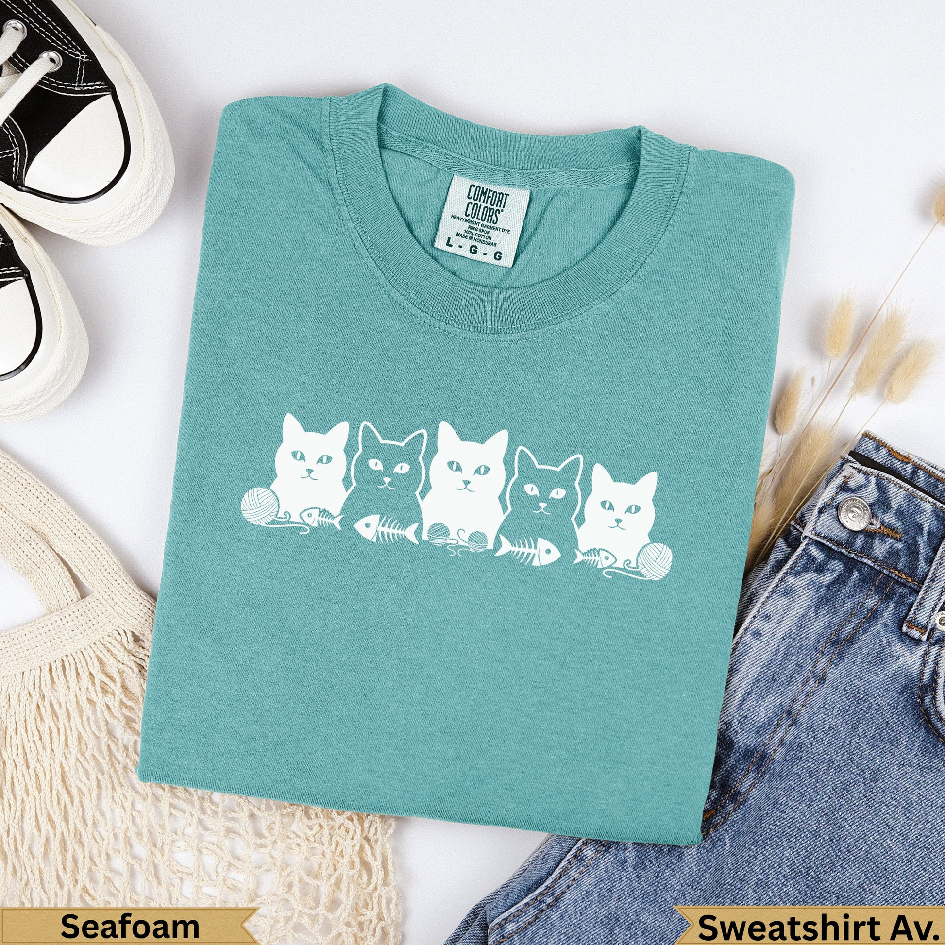 Teal Comfort Colors t-shirt with five white cat illustrations and "Seafoam" text.