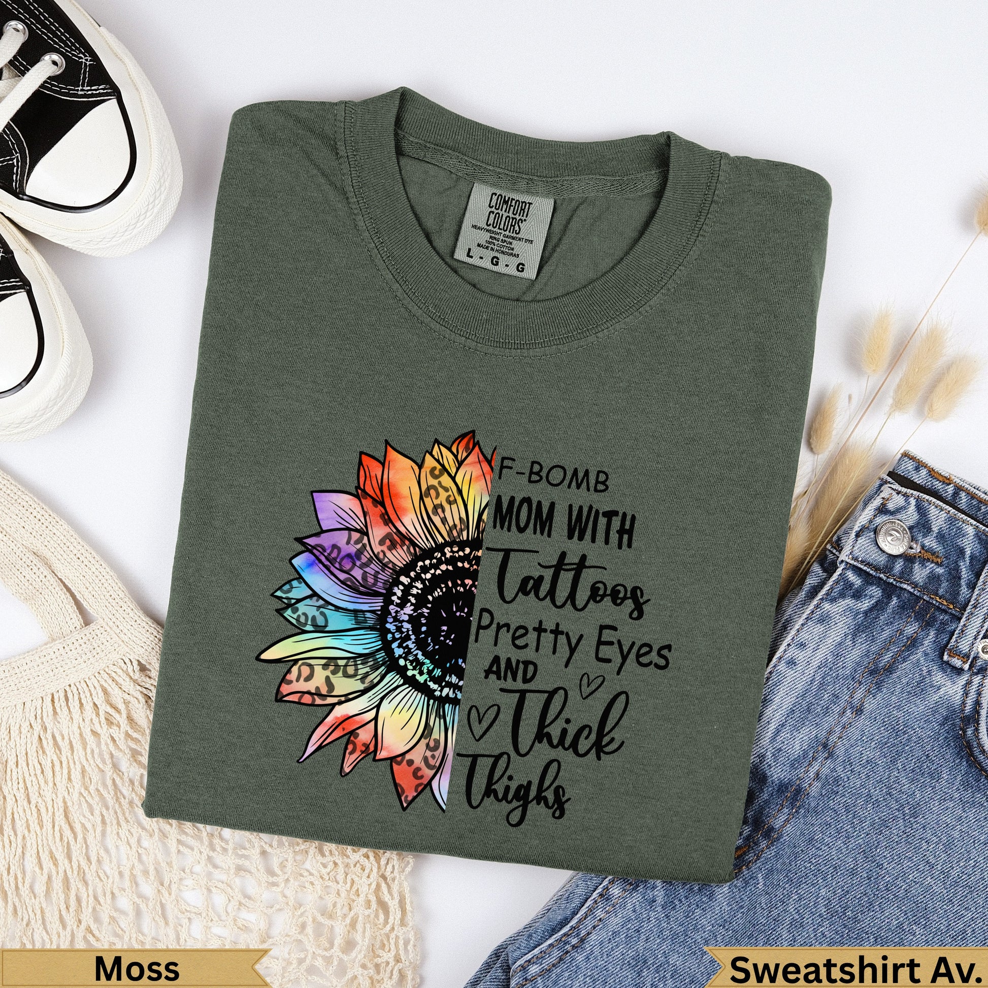 Green t-shirt with "F-Bomb Mom with Tattoos, Pretty Eyes and Thick Thighs" text and sunflower graphic.
