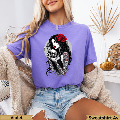 Tattooed woman holding a skull with a red rose in her hair, violet t-shirt.