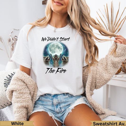 White crewneck sweatshirt with raccoons looking at a full moon and "We didn't start the fire" text.