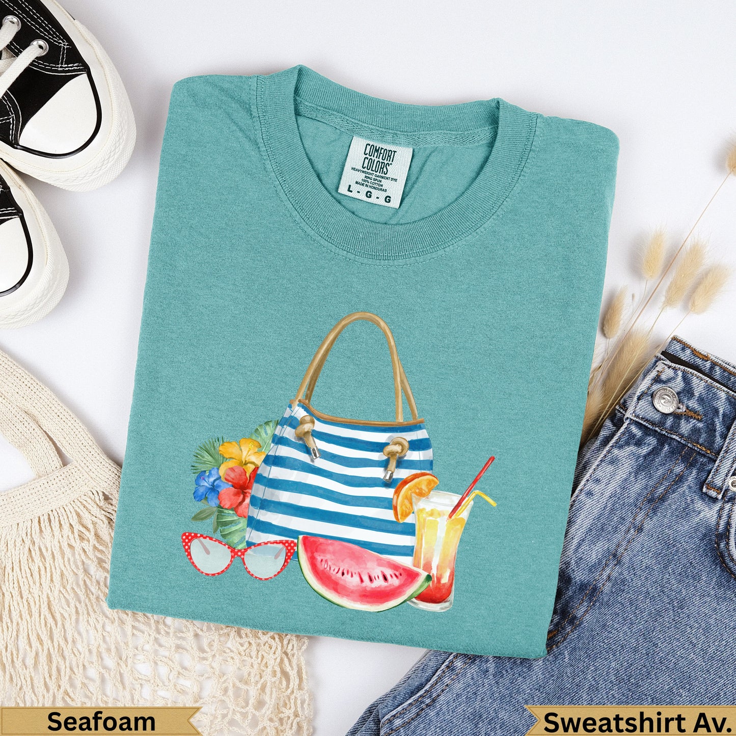 Teal sweatshirt with beach bag, fruit, and sunglasses graphic.