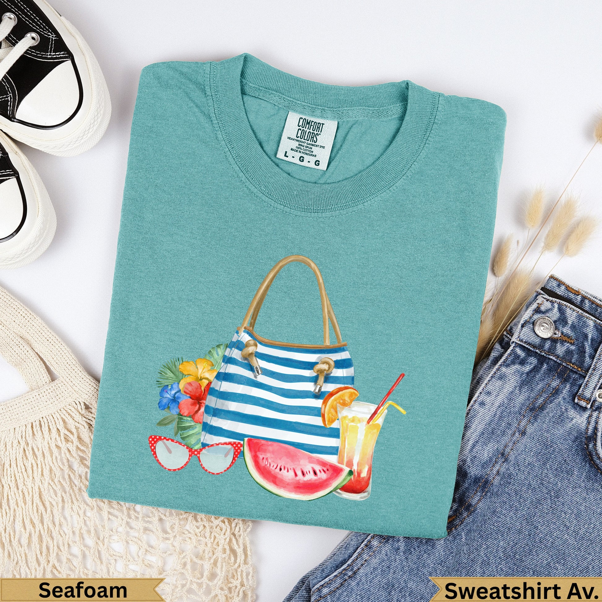 Teal sweatshirt with beach bag, fruit, and sunglasses graphic.