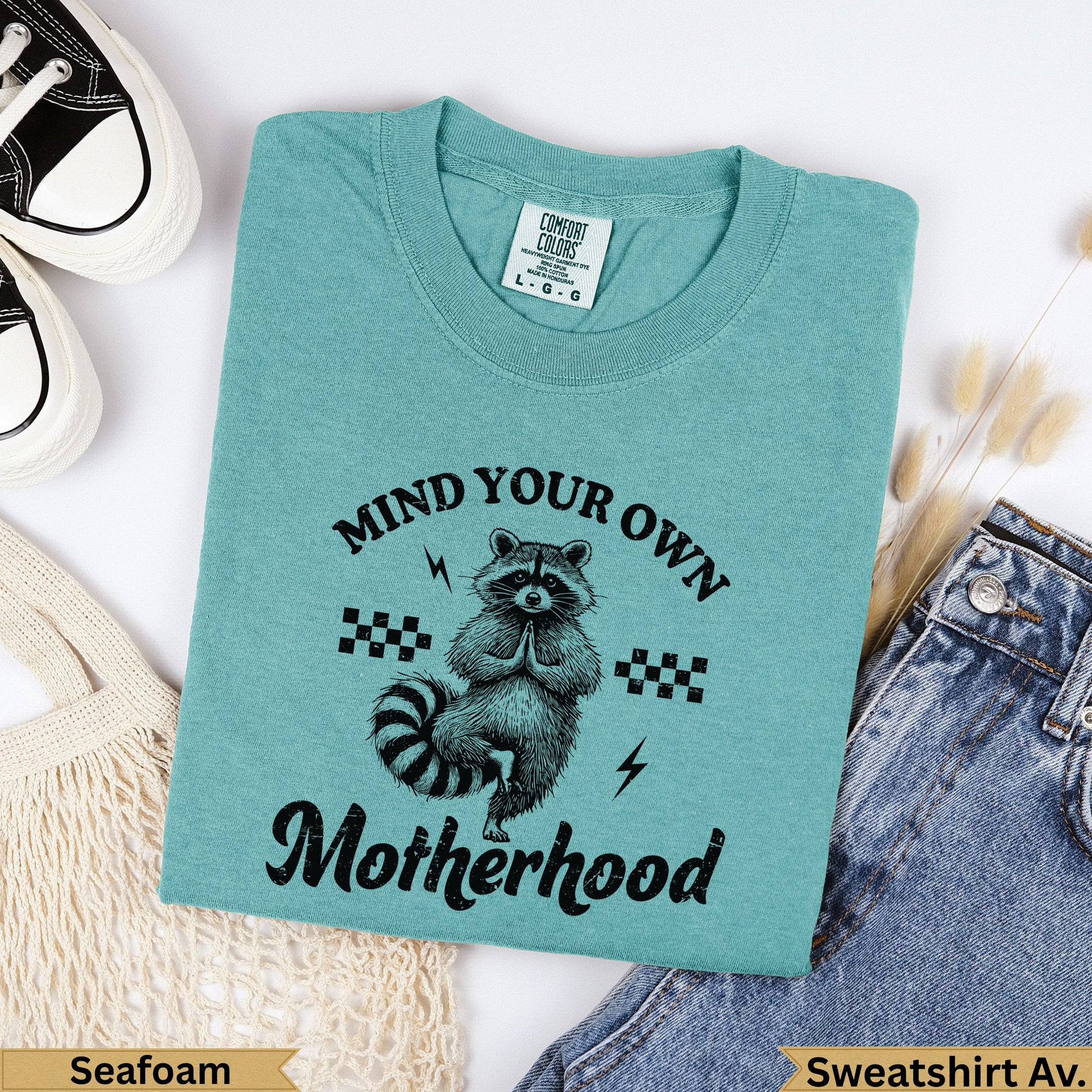 Teal sweatshirt with raccoon and "Mind Your Own Motherhood" text.