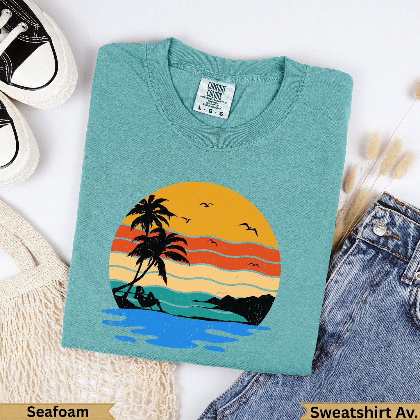 Teal sweatshirt with distressed sunset beach graphic and "Seafoam" label.