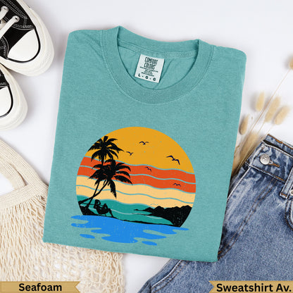 Teal sweatshirt with distressed sunset beach graphic and "Seafoam" label.