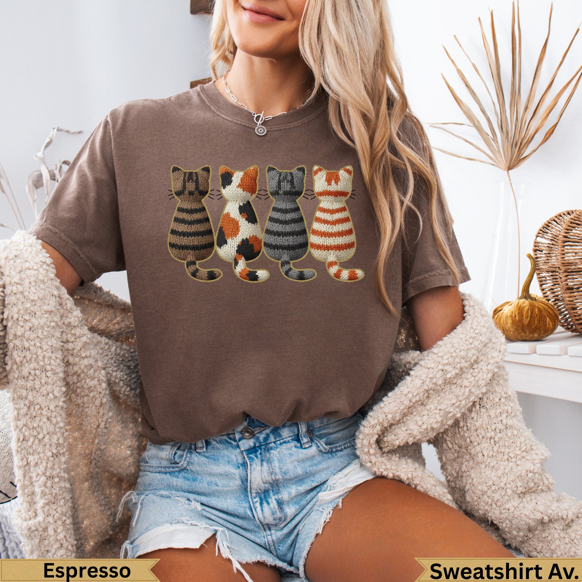 Four knit-style cats in a row on a brown t-shirt.