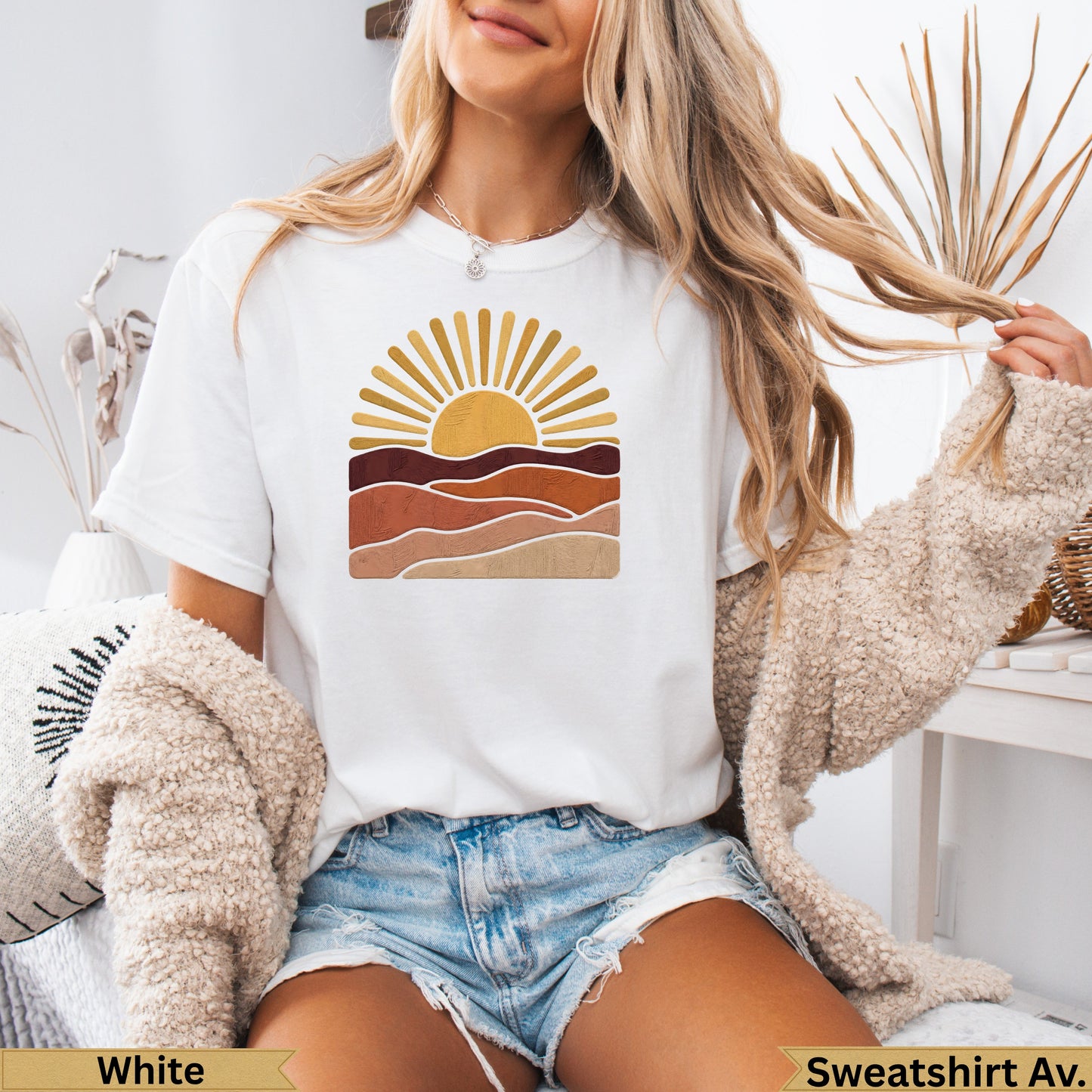 White t-shirt with a stylized sunset graphic over desert-like landscapes.