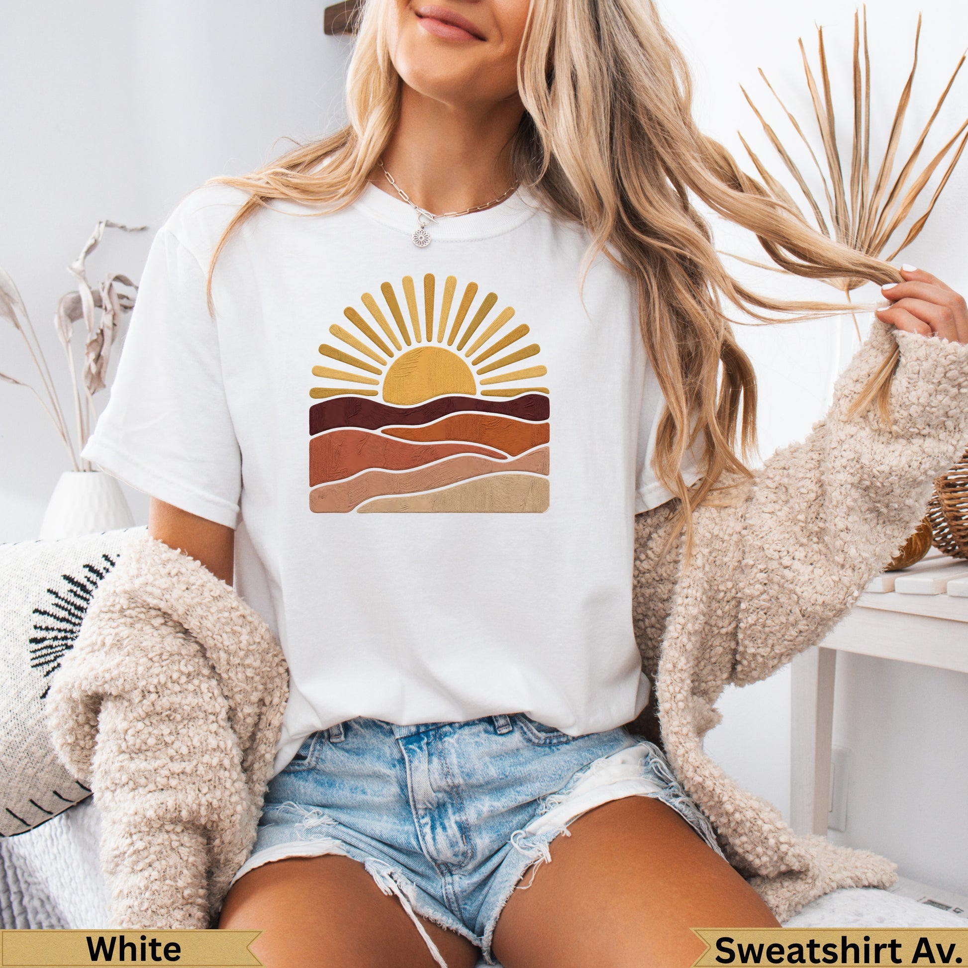 White t-shirt with a stylized sunset graphic over desert-like landscapes.