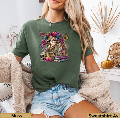 Woman wearing an olive green t-shirt with floral, butterfly, and skull graphic.