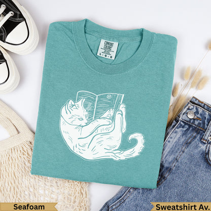 Teal sweatshirt with white cat illustration reading a book, "Seafoam" label.