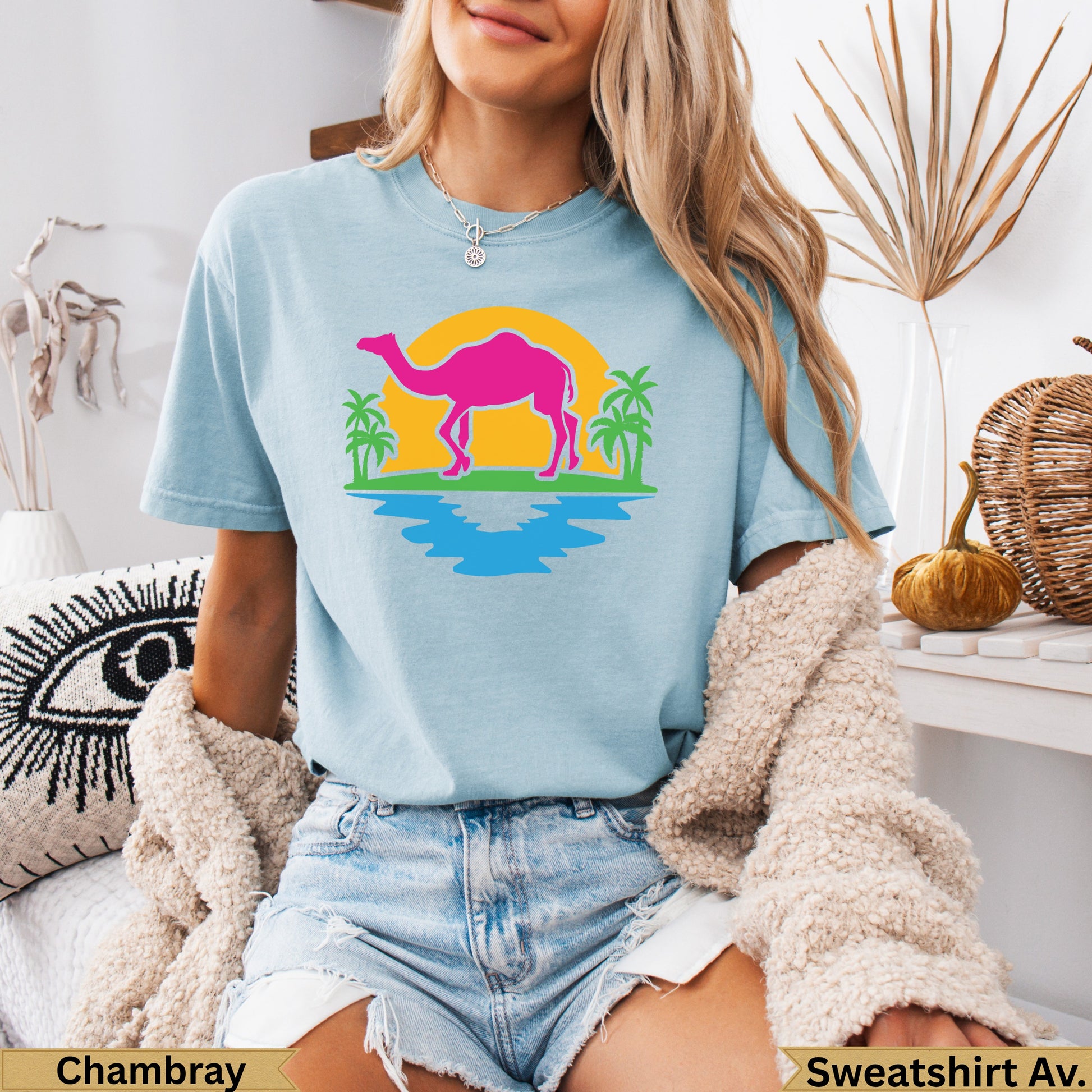 Light blue t-shirt with a neon pink camel silhouette on a sunset beach graphic.