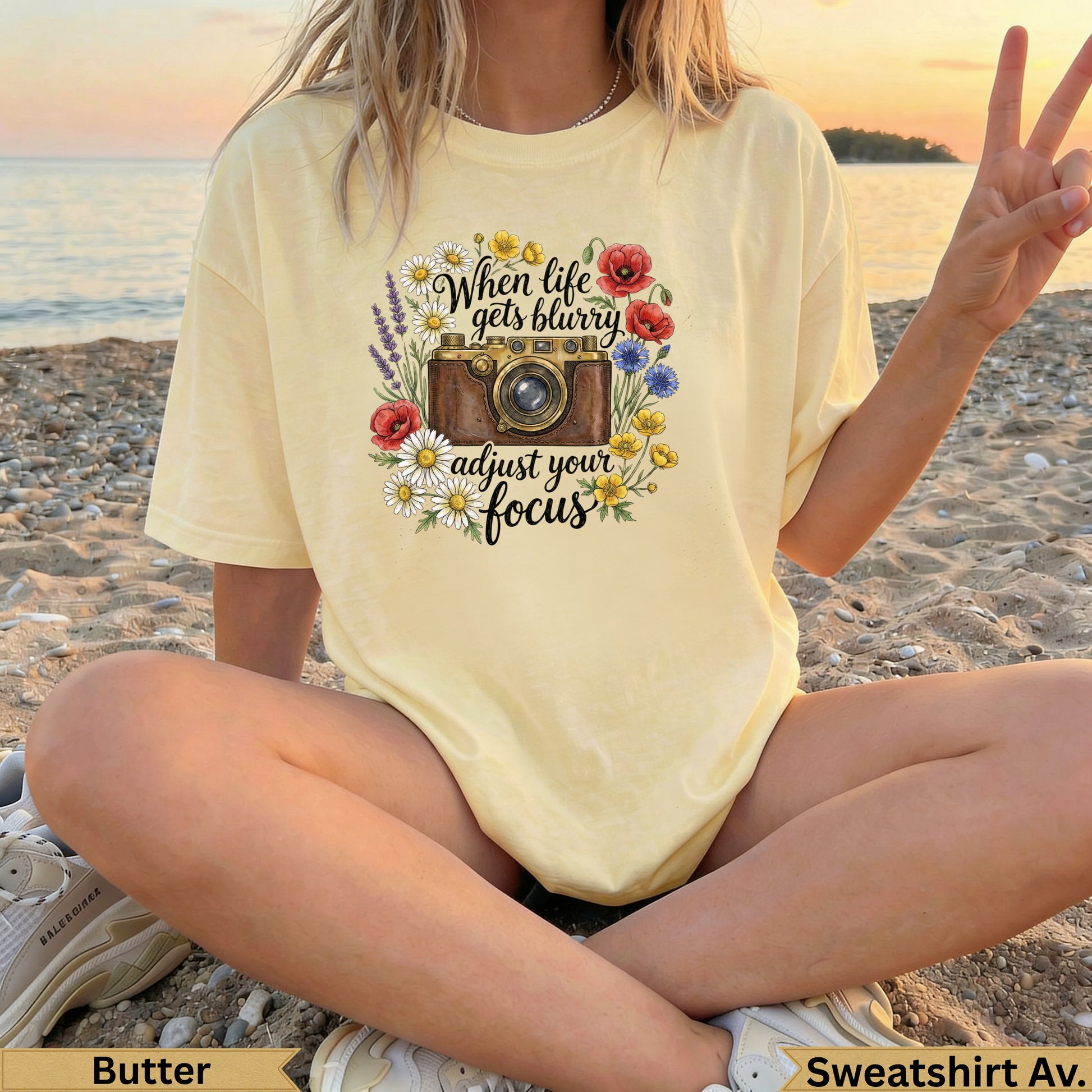 Butter yellow t-shirt with floral camera graphic reading "When life gets blurry adjust your focus".