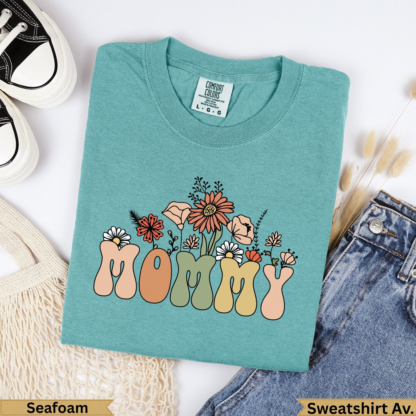 Teal t-shirt with "MOMMY" in colorful retro font and floral accents.