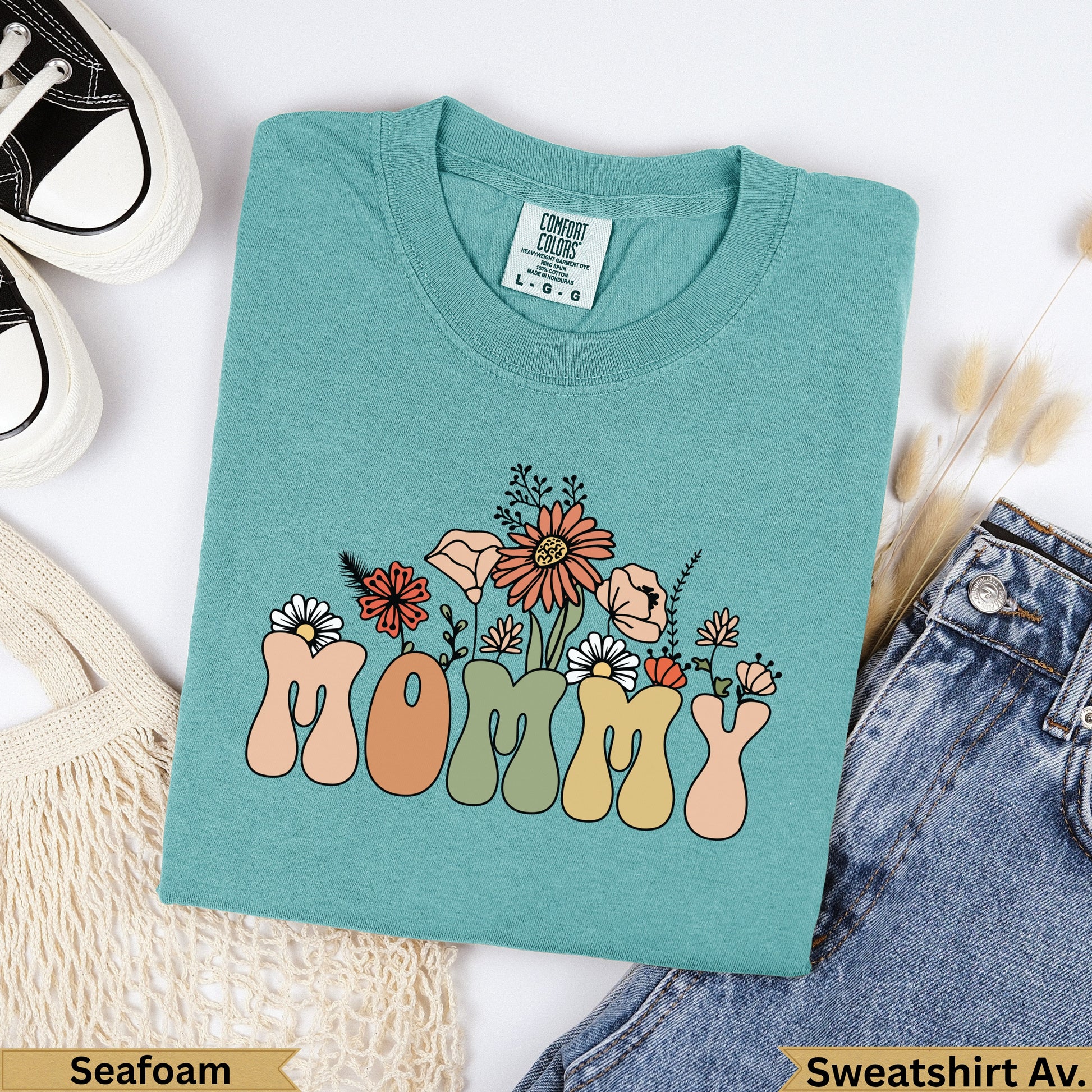 Teal t-shirt with "MOMMY" in colorful retro font and floral accents.
