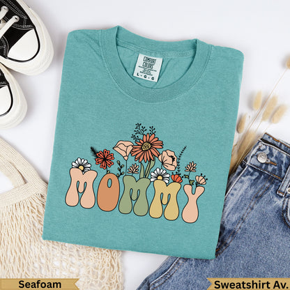 Teal t-shirt with "MOMMY" in colorful retro font and floral accents.