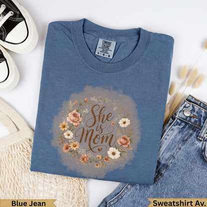 Blue Jean Comfort Colors sweatshirt with "She is Mom" floral wreath graphic.