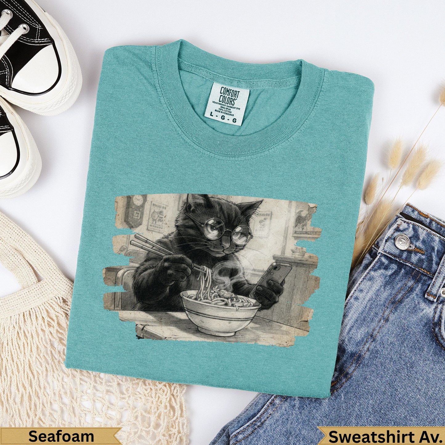 Black cat wearing glasses eats ramen, printed on a seafoam Comfort Colors sweatshirt.