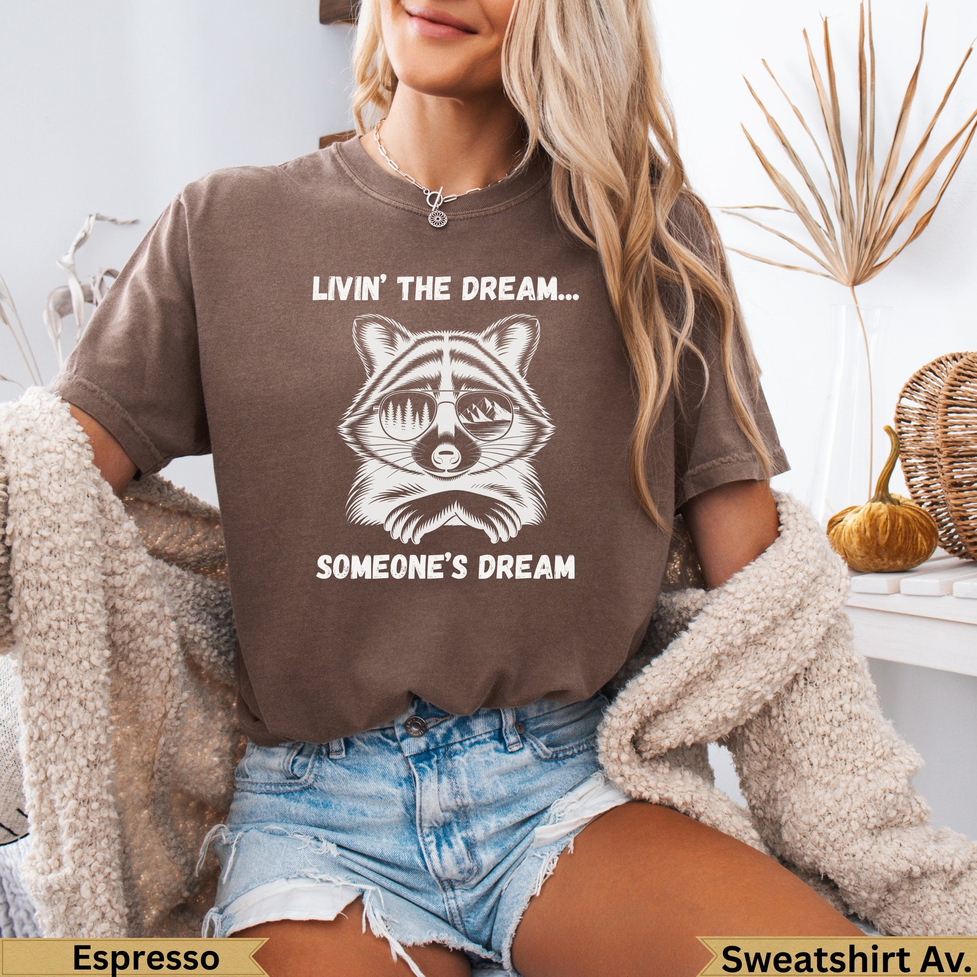 Brown t-shirt with sunglasses-wearing raccoon and "Livin' the dream... Someone's dream" text.
