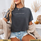 Dark grey t-shirt with "snacks, chaos, repeat" text worn by a woman.