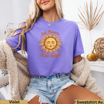 Purple t-shirt with sun graphic and "Eat Plants Shine Bright" text.