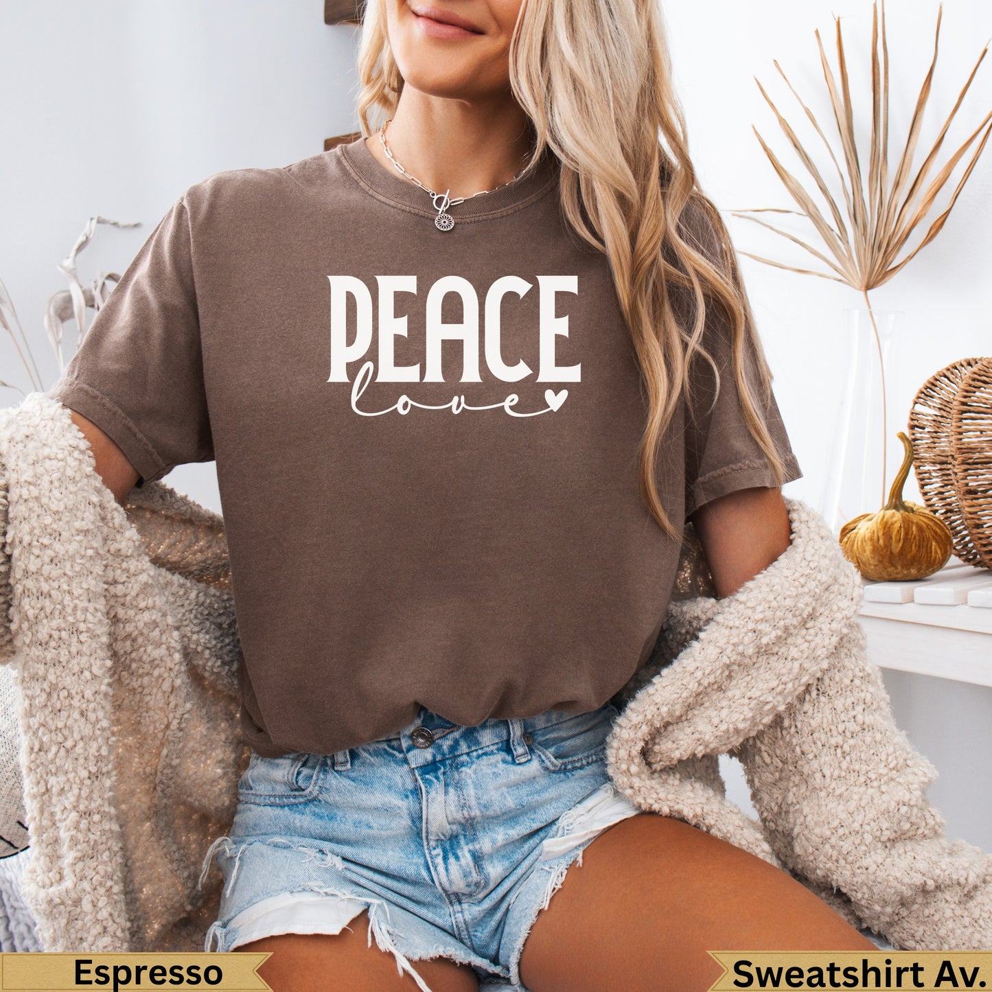 Woman in brown sweatshirt with "PEACE love" text, wearing denim shorts.