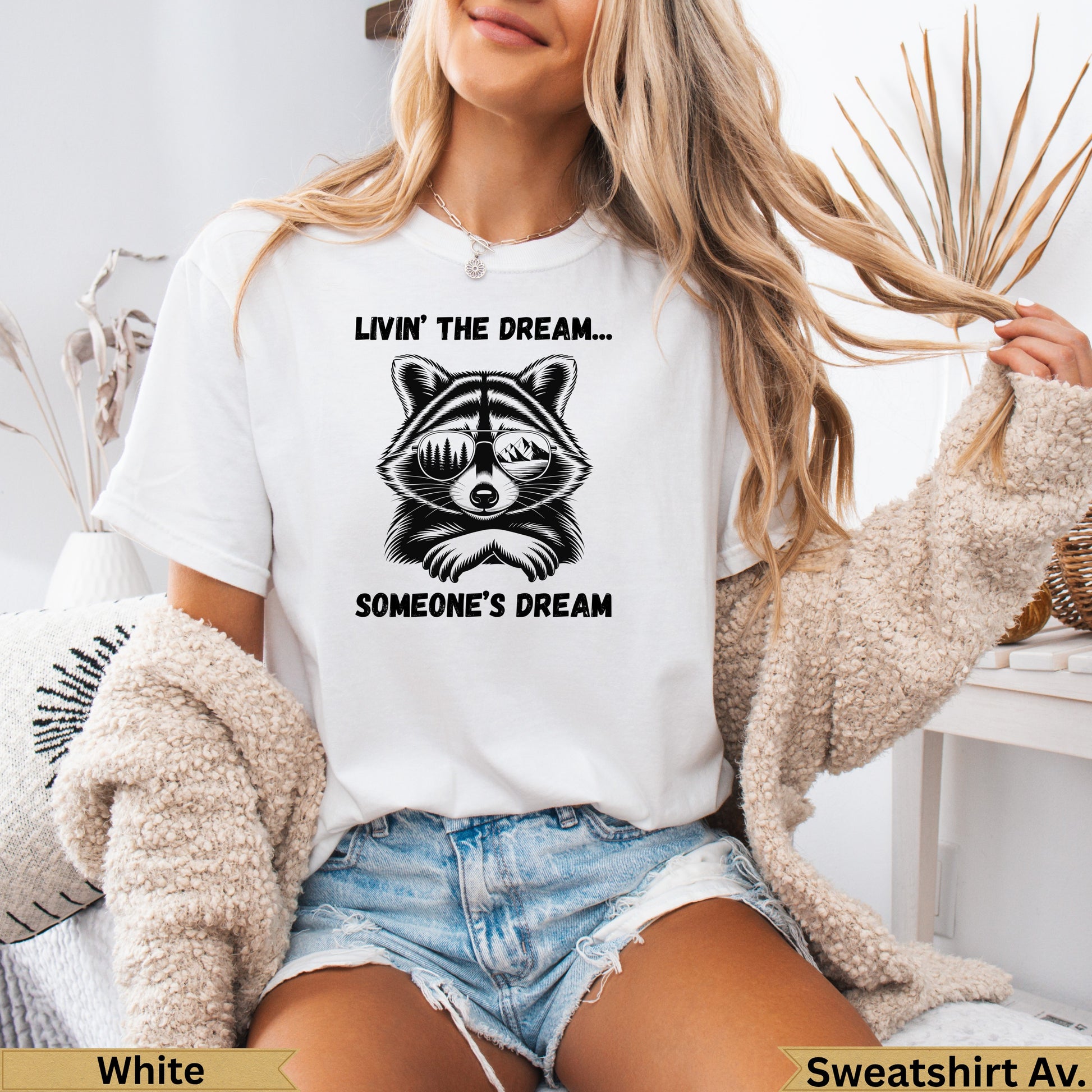 White t-shirt with a raccoon wearing sunglasses and text "Livin' the Dream... Someone's Dream".