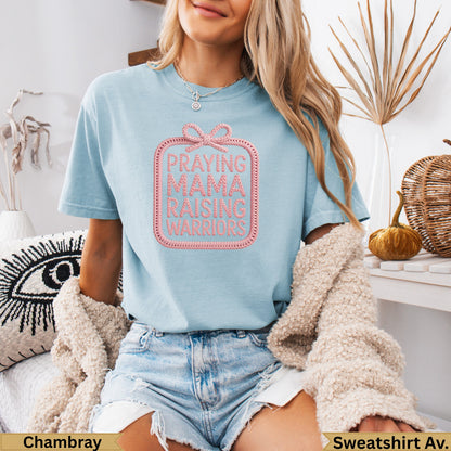 Light blue t-shirt with pink embroidered text "PRAYING MAMA RAISING WARRIORS."
