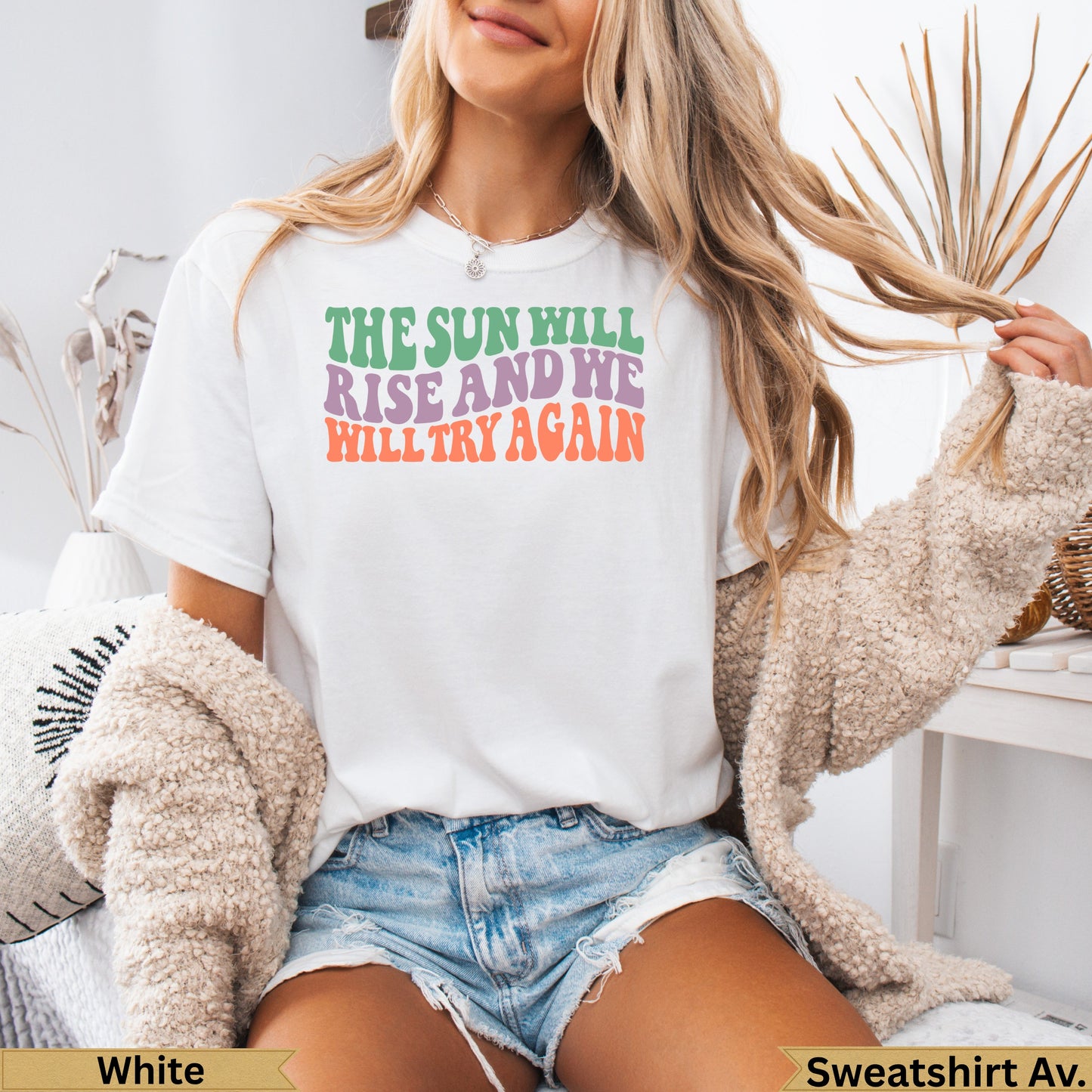 White t-shirt with colorful text: "The sun will rise and we will try again."