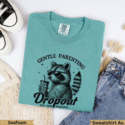 Teal t-shirt with raccoon wearing sunglasses and holding a drink, "Gentle Parenting Dropout" text.
