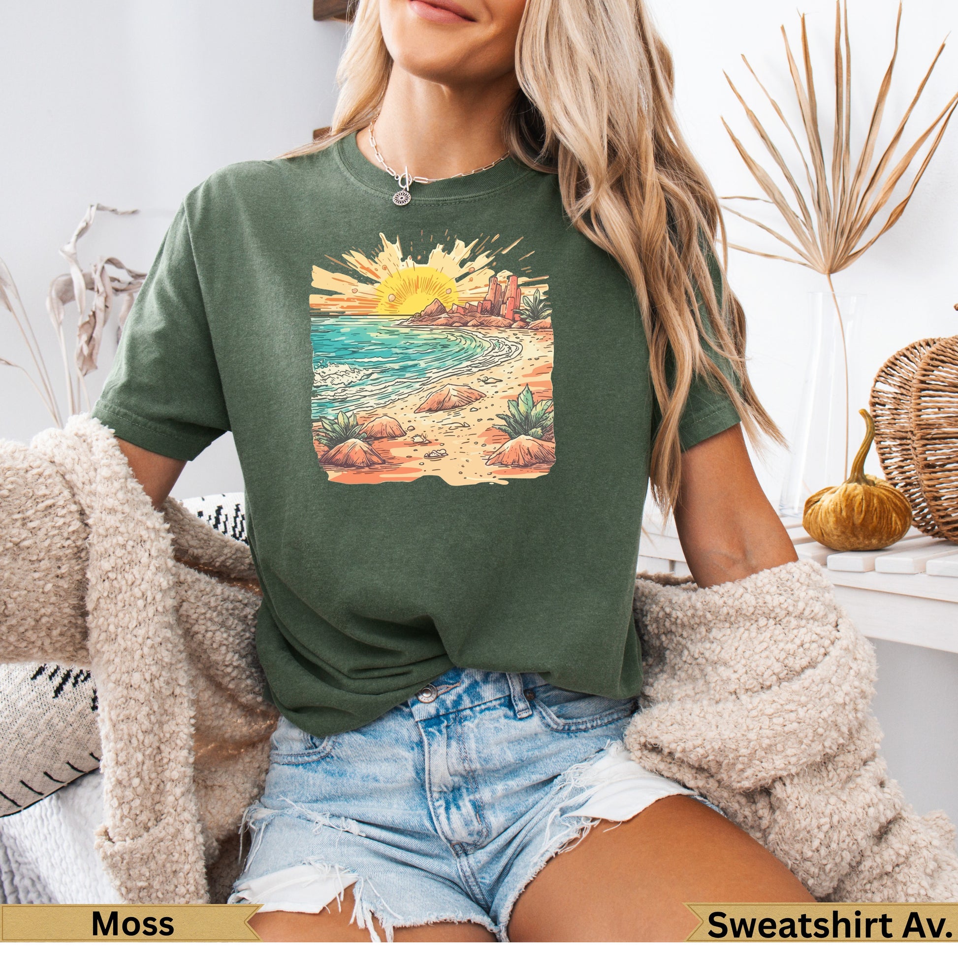 Green t-shirt with desert beach sunset graphic, worn by a woman.