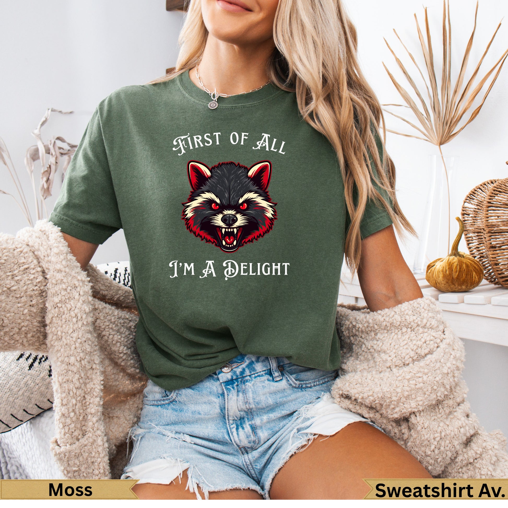 Green t-shirt with raccoon graphic and text "FIRST OF ALL I'M A DELIGHT".