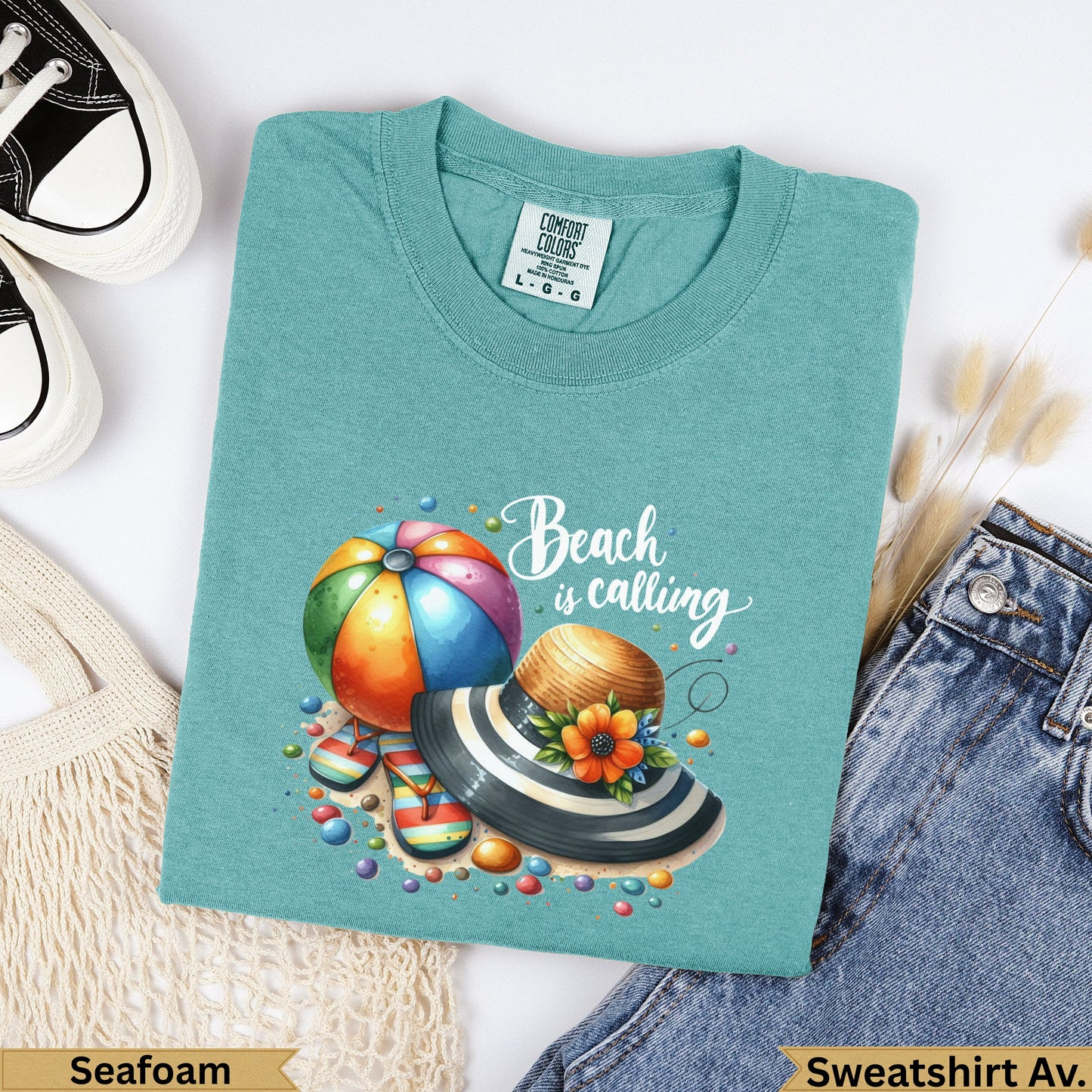 Teal t-shirt with "Beach is calling" graphic featuring beach ball, hat, and sandals.