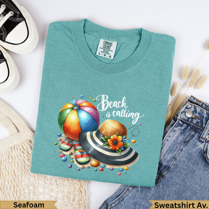 Teal t-shirt with "Beach is calling" graphic featuring beach ball, hat, and sandals.