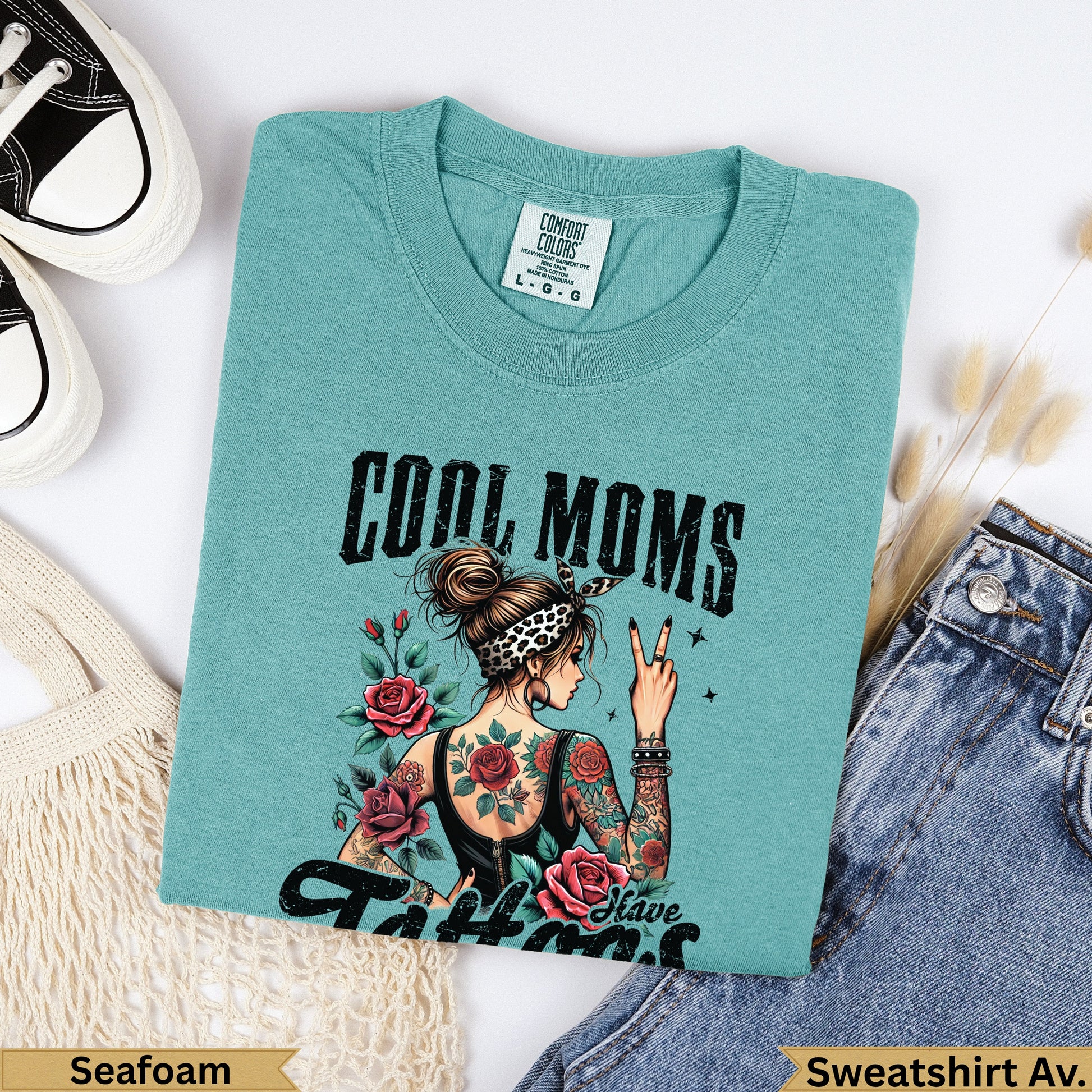Teal t-shirt with "COOL MOMS" and roses graphic, woman with tattoos.