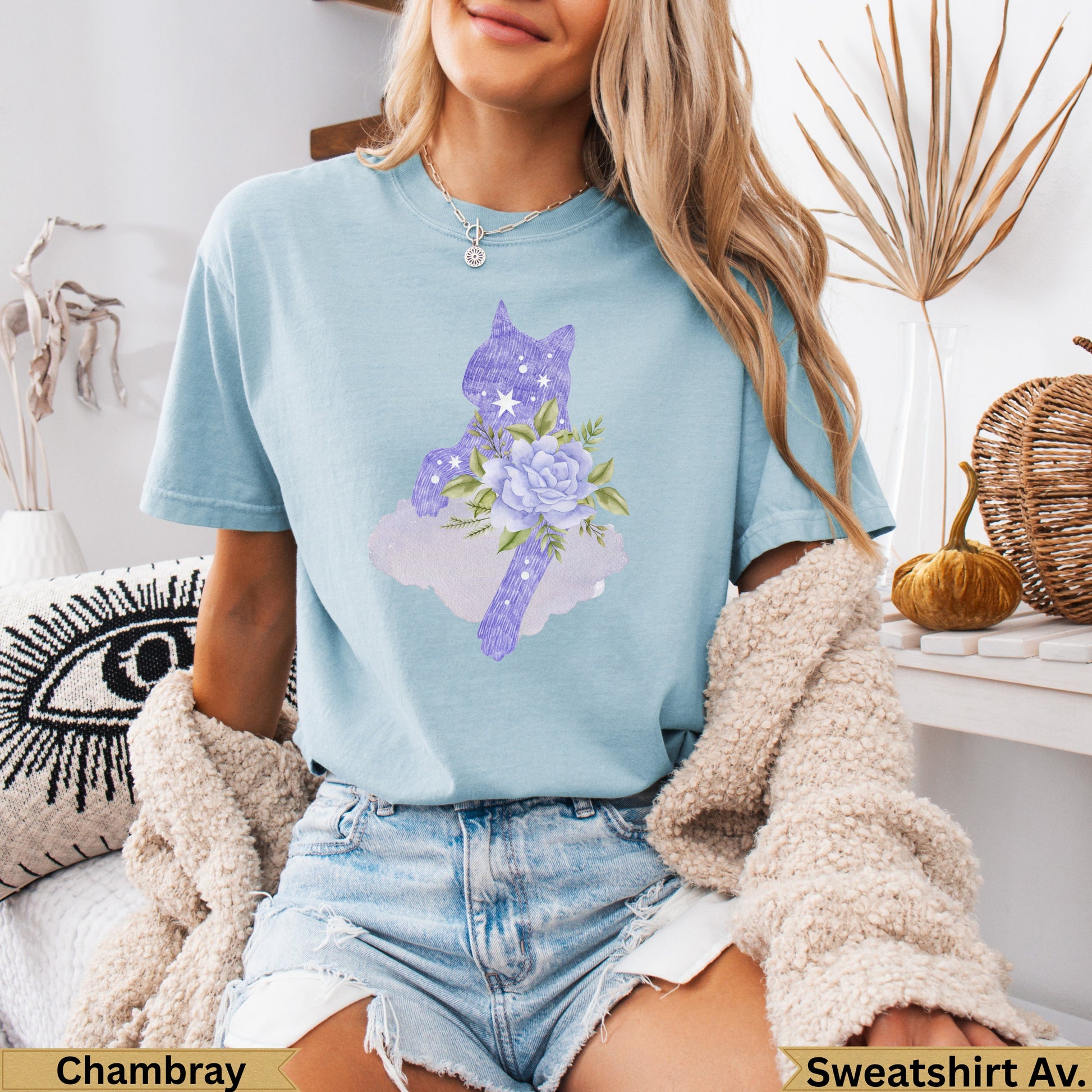 Light blue t-shirt with purple cat and floral graphic, worn by a woman.