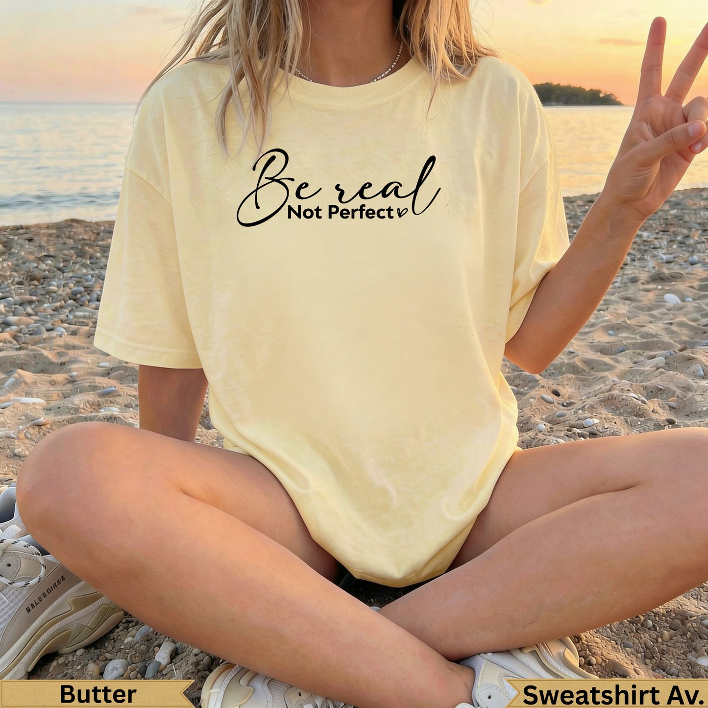 Light yellow t-shirt with "Be real Not perfect" text, worn by a person on the beach.