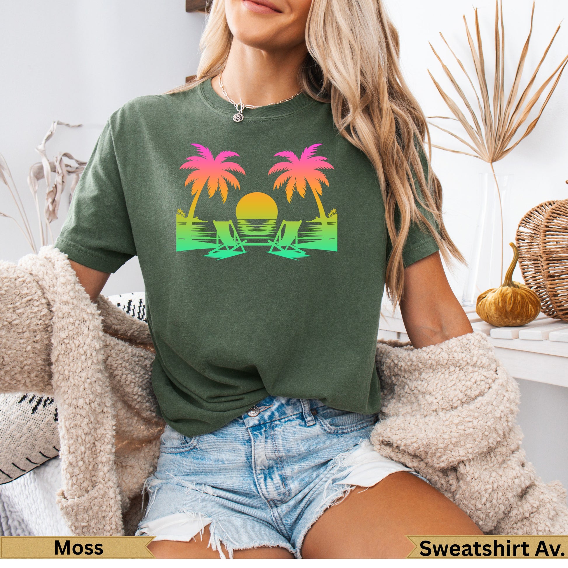 Green t-shirt with sunset, palm trees, and beach chairs graphic.