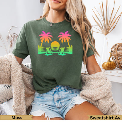 Green t-shirt with sunset, palm trees, and beach chairs graphic.