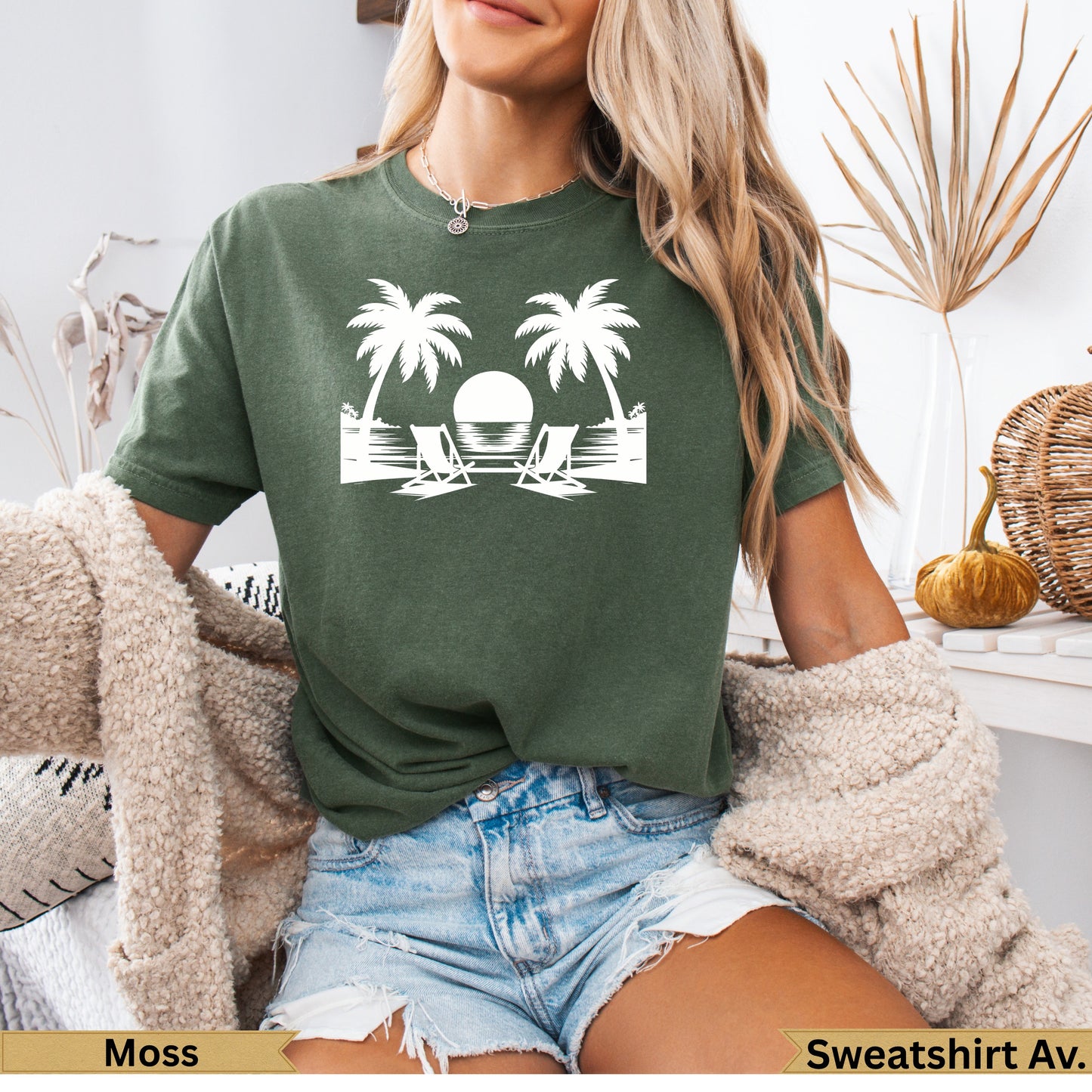 Green t-shirt with white graphic of two palm trees, beach chairs, and sun.